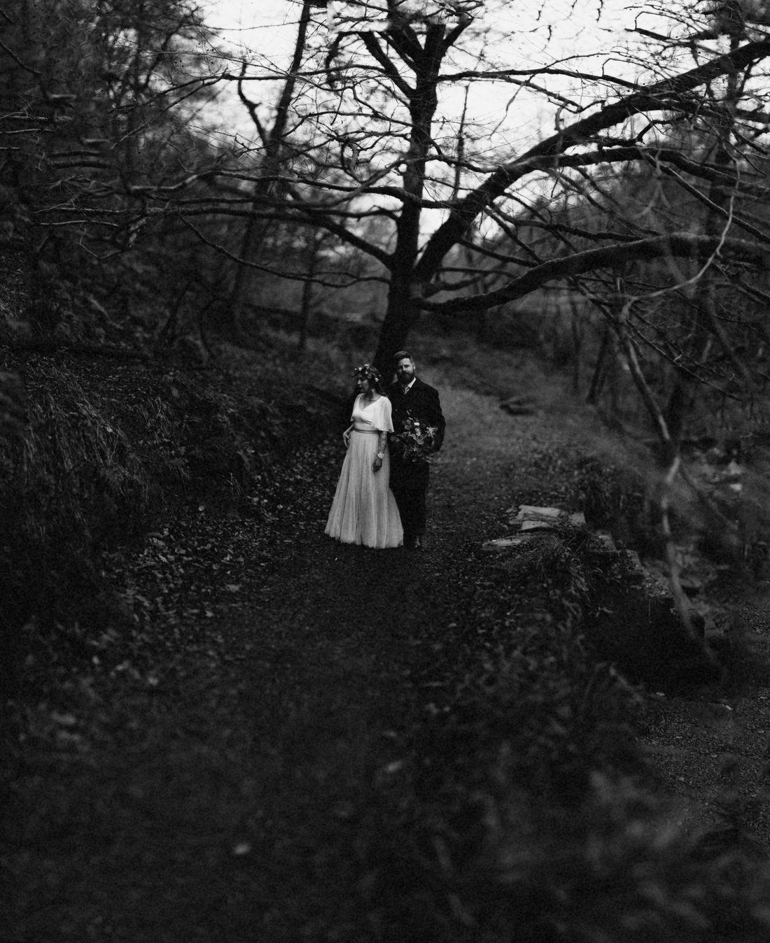 A couple small beside a great bare tree in winter, black and white