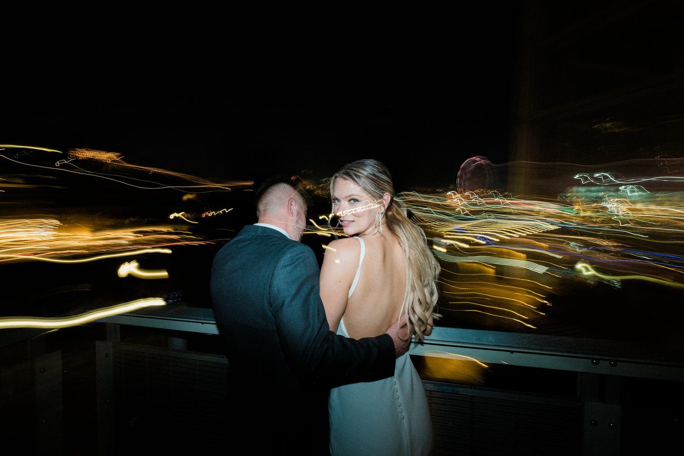 Jackie and Jared at night in Montréal, city light trails behind them